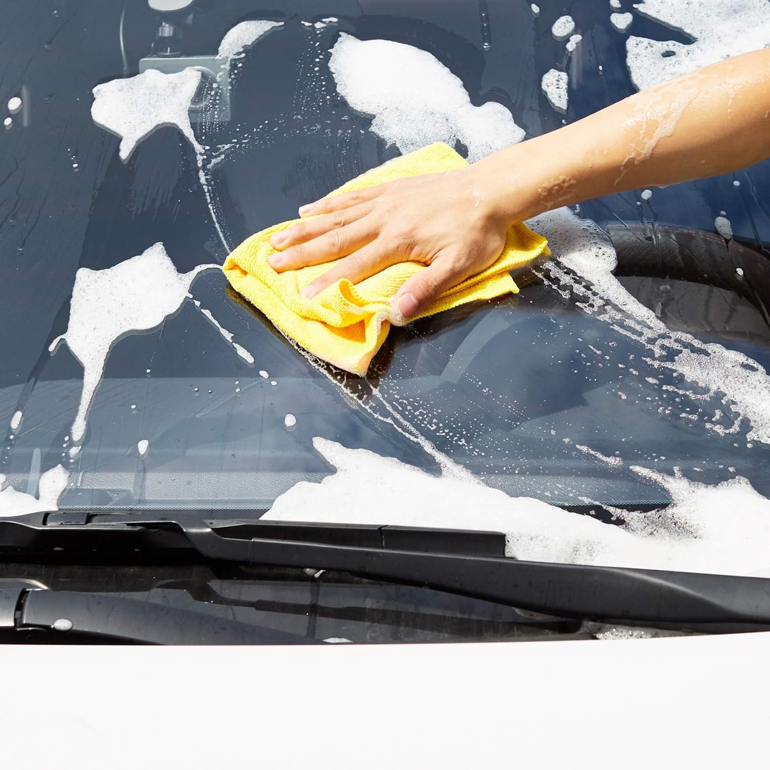 Demonstrates the proper technique for cleaning a car windshield, showing the product in use.