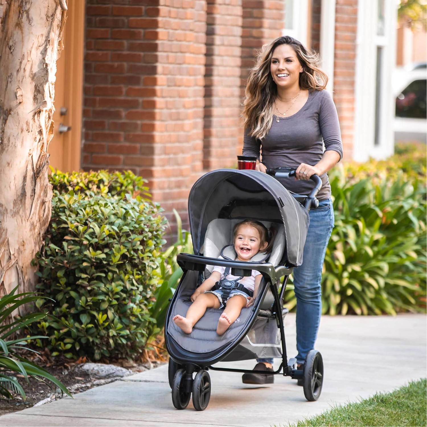 Shows the stroller being used in a real-life setting, emphasizing its practicality for everyday family activities.