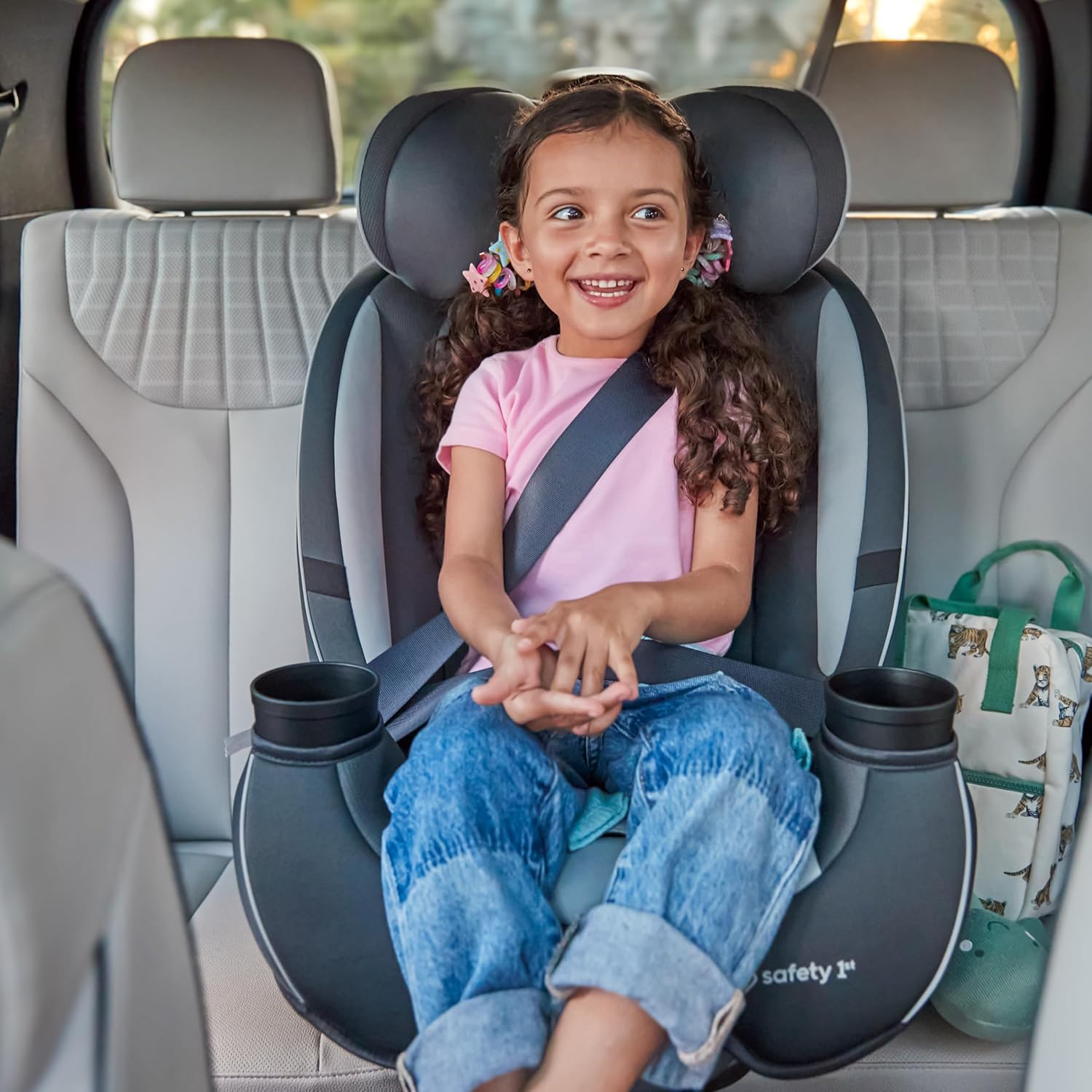 Shows a happy child securely seated in a car seat, demonstrating the product's safety and comfort for young passengers.