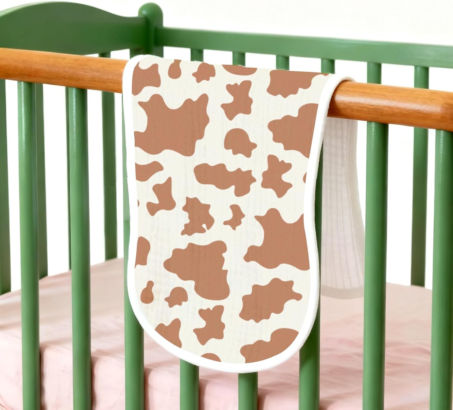 Shows how the cow print blanket looks in a real nursery setting, helping shoppers visualize the product in use.