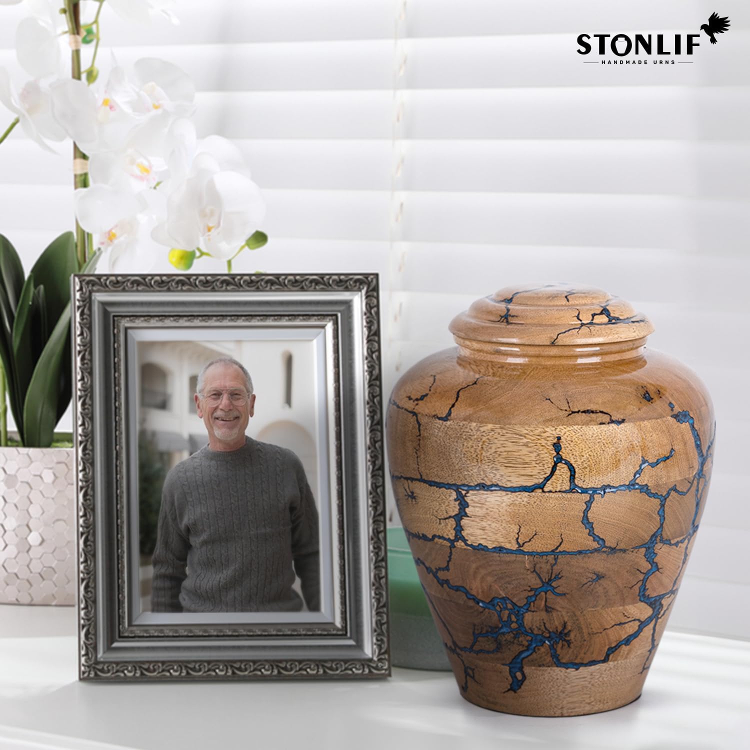 Showcases the handcrafted urn product alongside a framed photo to demonstrate its use as a memorial keepsake.